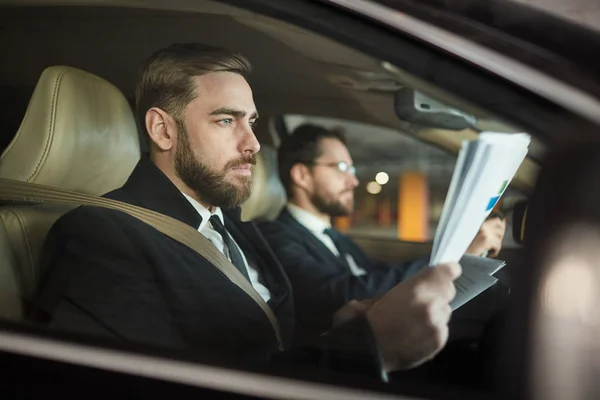 Σοβαρός Γενειοφόρος Επιχειρηματίας Που Κάθεται Στο Αυτοκίνητο Και Διαβάζει Συμβόλαιο — Φωτογραφία Αρχείου