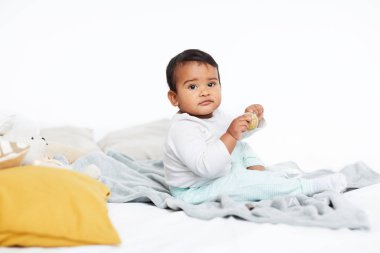 Cute African babyl boy sitting on the bed and playing with toys