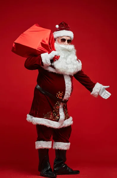 Portret Świętego Mikołaja Okularach Przeciwsłonecznych Czerwonym Woreczkiem Prezentami Świątecznymi Stojącym — Zdjęcie stockowe