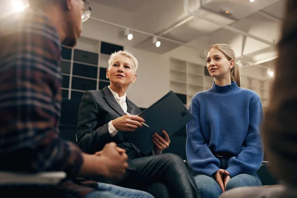 Mature Businesswoman Short Blond Hair Holding Clipboard Listening Young People — Stock Photo, Image