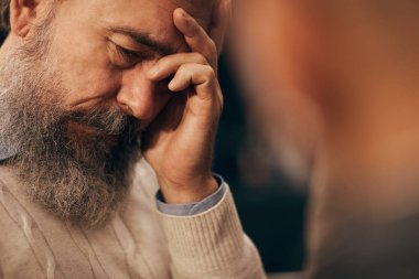 Sakallı yaşlı adam çok üzgün görünüyor. Oturup kadına sorunlarını anlatıyor.