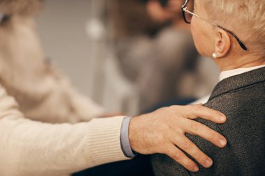 Olgun bir adamın, kadının omzuna elini koyması, konuşması ve destek vermesi.