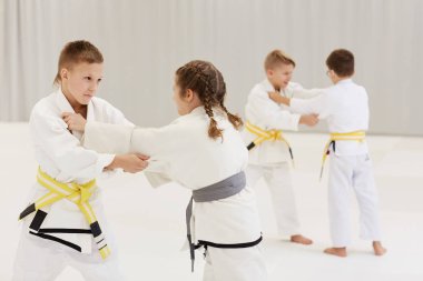 Beyaz kimonolu bir grup çocuk karate eğitimi sırasında bu teknikleri uyguluyor.