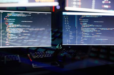 Karanlık ofise yeni bir yazılım yükleyen iki bilgisayar monitörü görüntüsü