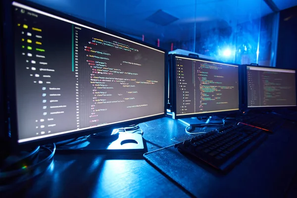 Image of computer monitors updating the software standing on the table in dark room