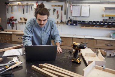 Marangoz çalışırken dizüstü bilgisayar kullanıyor