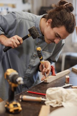 Marangoz tahta ve çekiçle çalışır.