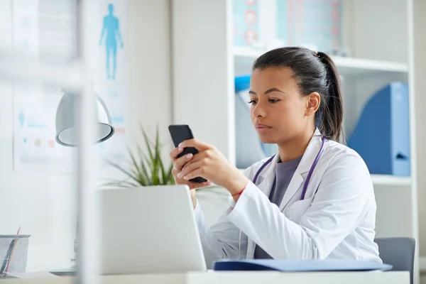 Médico femenino usando teléfono en el consultorio —  Fotos de Stock