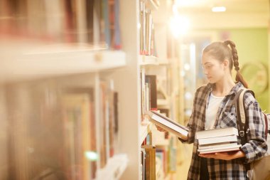 Okumak için bir kitap seçen kadın