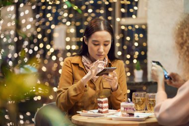 Woman using phone during meeting in cafe