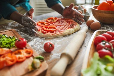 Adam masada pizza yapıyor.