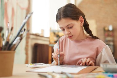 Little girl painting at the table