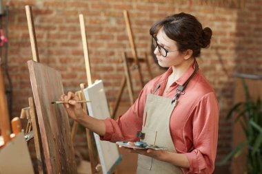 Woman painting on easel at art studio