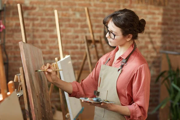 Woman painting on easel at art studio — Stockfoto