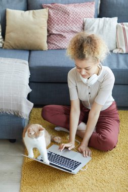 Yerde dizüstü bilgisayar kullanan kadın.