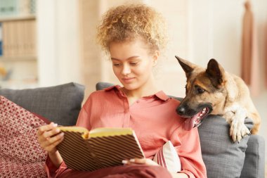 Woman reading a book with dog