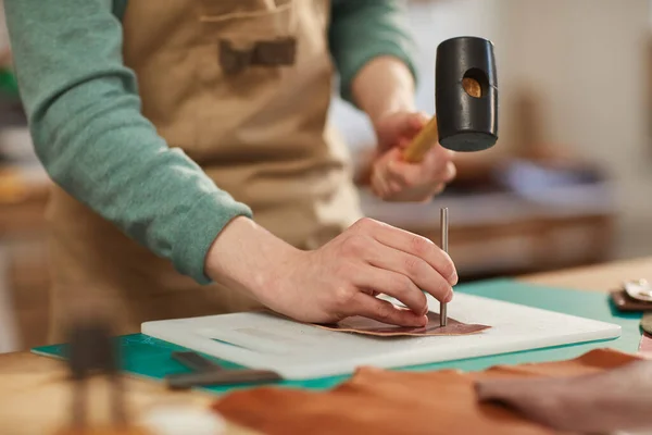 Hombre perforando agujeros en material de cuero — Foto de Stock