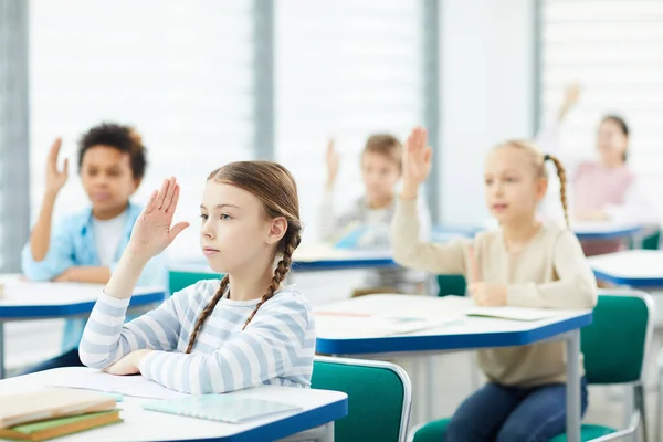 Estudantes levantando as mãos em sala de aula — Fotografia de Stock