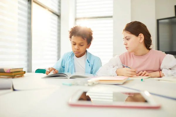 Menino e menina na mesa da escola — Fotografia de Stock