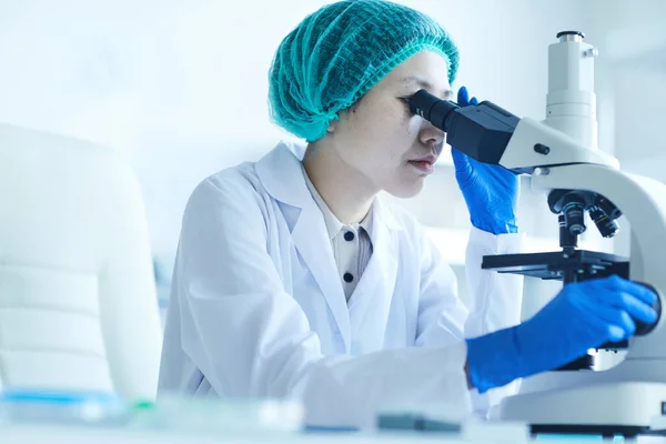 Mujer examinando muestras con microscopio —  Fotos de Stock