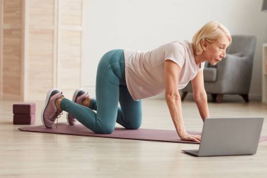 Üst düzey kadın yerde egzersiz yapıyor.