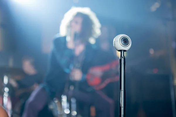 Rio de Janeiro, Brazil - August 13, 2016: 360 degree camera shaped as an eyeball on a stick recording a scene with a live rock band playing which is out of focus blurred in the background