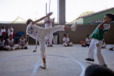 Rio de Janeiro, Brezilya - 9 Ağustos 2016: Brezilya capoeira sınıfındaki çocuklar ve arka planda berimbau enstrümanı çalan bir öğretmen kenar mahallelerdeki bir spor salonunda