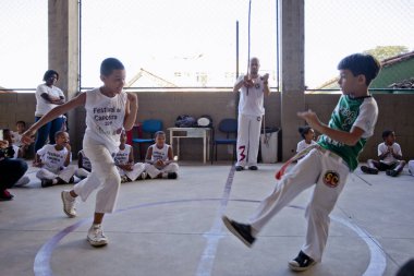 Rio de Janeiro, Brezilya - 9 Ağustos 2016: Brezilya capoeira sınıfındaki çocuklar ve arka planda berimbau enstrümanı çalan bir öğretmen kenar mahallelerdeki bir spor salonunda