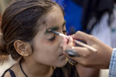 Rio de Janeiro, Brezilya - 2 Kasım 2019: Copacabana Bulvarı 'nda Cadılar Bayramı zombi yürüyüşünden önce genç bir kızı boyayan makyaj sanatçısına yakın çekim 