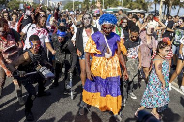Rio de Janeiro, Brezilya - 2 Kasım 2019: Cadılar Bayramı Zombi Yürüyüşü kalabalık Ölüler Günü 'nde Copacabana Bulvarı' nda güneşli bir günde arka planda palmiye ağaçları ile ilerliyor.