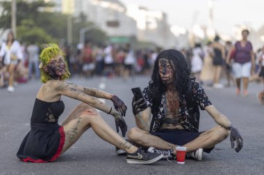 Rio de Janeiro, Brezilya - 2 Kasım 2019: Ölüler Günü 'nde Cadılar Bayramı yürüyüşü, Finados, Copacabana' da asfalt zeminde oturan bir çiftle birlikte