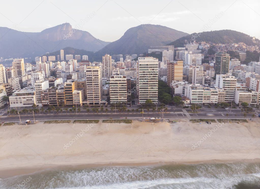 Empty beach in early morning Ipanema neighbourhood in Rio de Janeiro with the Corcovado and Sugarloaf mountain in the background at a hazy colourful sunrise