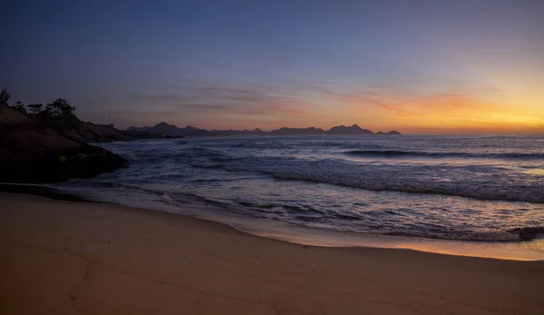 在里约热内卢的Arpoador魔鬼海滩 黎明时分 灿烂而温暖的日出 波涛汹涌 反射出太阳的橙色 还有一片原始的沙滩 图库照片