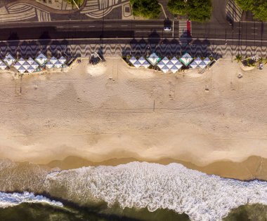 Boş Copacabana plajında tepeden aşağı manzara. Bulvarda plaj barları, dekore edilmiş kaldırımlar ve sabahın erken saatlerinde gelen dalgalar.