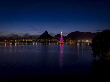 Gün batımında Rio de Janeiro gölünün ortasındaki yüzen Noel ağacının ışıkları morumsu renk düzeniyle.