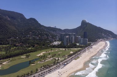 Sahil manzaralı Conrado golf sahası önü plajlı ve Two Brother Mountain ve Corcovado dağı gecekondu şehri Rocinha 'nın arkasında mavi gökyüzüne karşı.