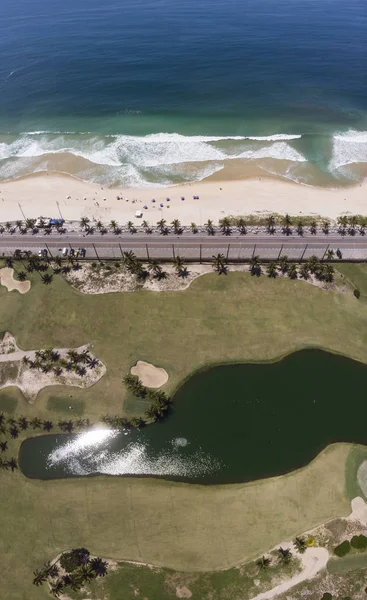 里约热内卢圣康拉多高尔夫俱乐部的空中 棕榈树 沙丘和阳光映照在滨海海滩旁边的人工湖中 波浪被道路和林荫大道隔开 图库照片