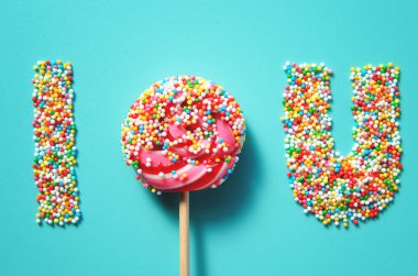 Kırmızı çizgili renkli lolipop şekeri ve tatil için mavi nane arkaplanına serpiştirilmiş şekerler.