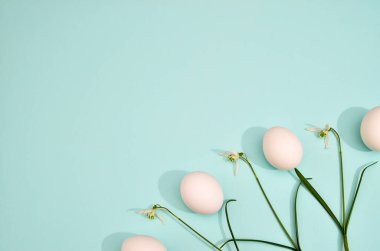 White eggs with green myrtle leaves pattern on mint color background. Spring and Easter holiday concept with copy space.