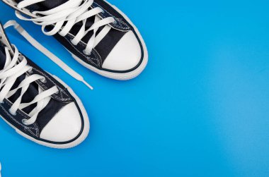 Mavi arka planda duran bir çift mavi spor ayakkabı. Üst Manzara. Flatlay. Telif uzayı merkezi. Metin için boşluk