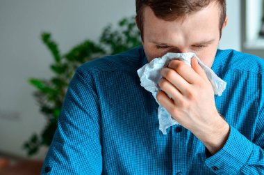 Genç bir işadamının iş yerindeki bir mendille burnunu silmesi. Gerçek problem, soğuk ve soğuk, tıbbi tasarım için arka plan