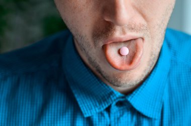 Mavi gömlekli bir işadamı ağzı ve dilinde bir hap. Gerçek problem, soğuk ve soğuk, tıbbi tasarım için arka plan