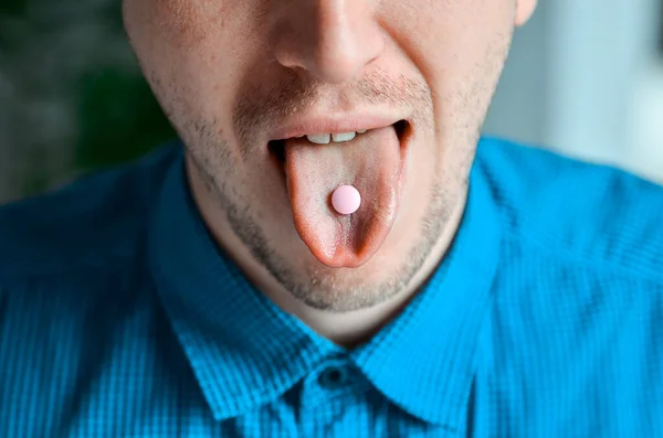 Mouth of businessman in blue shirt and a pill on his tongue. Actual problem, cold and chill, background for medical design