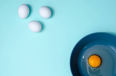 Bir sürü beyaz yumurta ve mavi bir tabak, üzerinde sarı ve beyaz nane mavisi arka planda. Kırık yumurta, mesaj için boşluk