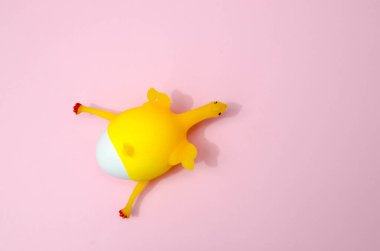 Pembe arka planda lateks sarı oyuncak tavuk ve tavuk yumurtası. Paskalya konsepti. Üst görünüm, metin için boşluk