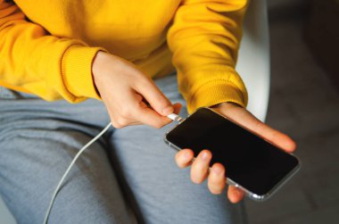 Bir adam akıllı telefonu USB şarj portlarıyla prize takıyor. Tek atış.