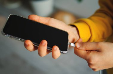 Bir adam akıllı telefonu USB şarj portlarıyla prize takıyor. Tek atış.