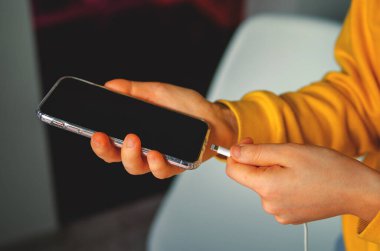 Bir adam akıllı telefonu USB şarj portlarıyla prize takıyor. Tek atış.