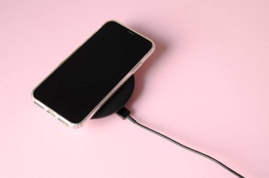 Akıllı telefon ve kablosuz şarj arkaplanda izole edilmiş. Cep telefonu şarj ediliyor
