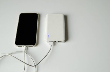 Beyaz arka planda izole edilmiş elektrik bankasıyla akıllı telefon şarjı çekimleri. Cep telefonu şarj ediliyor